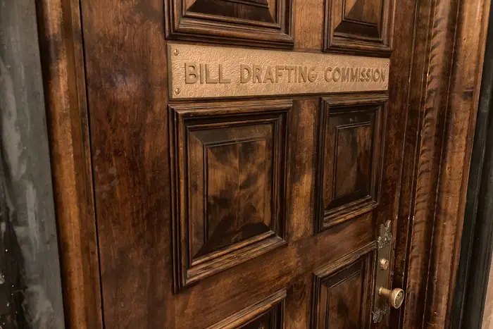 A wooden door at the state Capitol in Albany with a sign saying "bill drafting commission."